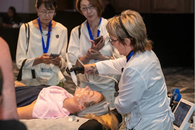 Healthcare professionals observe hands-on medical training demonstration with mannequin at professional conference.