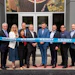 Group of business professionals holding blue Kerry ribbon at ribbon-cutting ceremony outside building