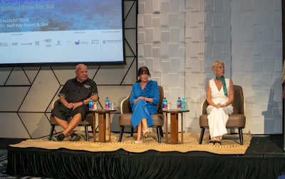 Three panelists seated on stage during a conference discussion about ocean conservation at Fiji Nadi Bay Resort.